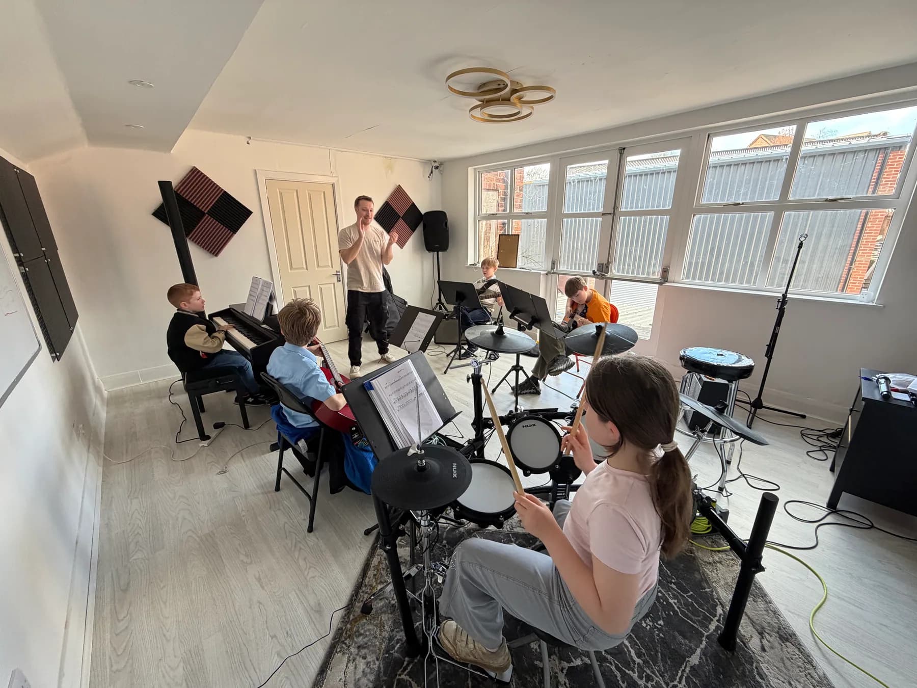 Apollo students rehearsing as a band with their teacher