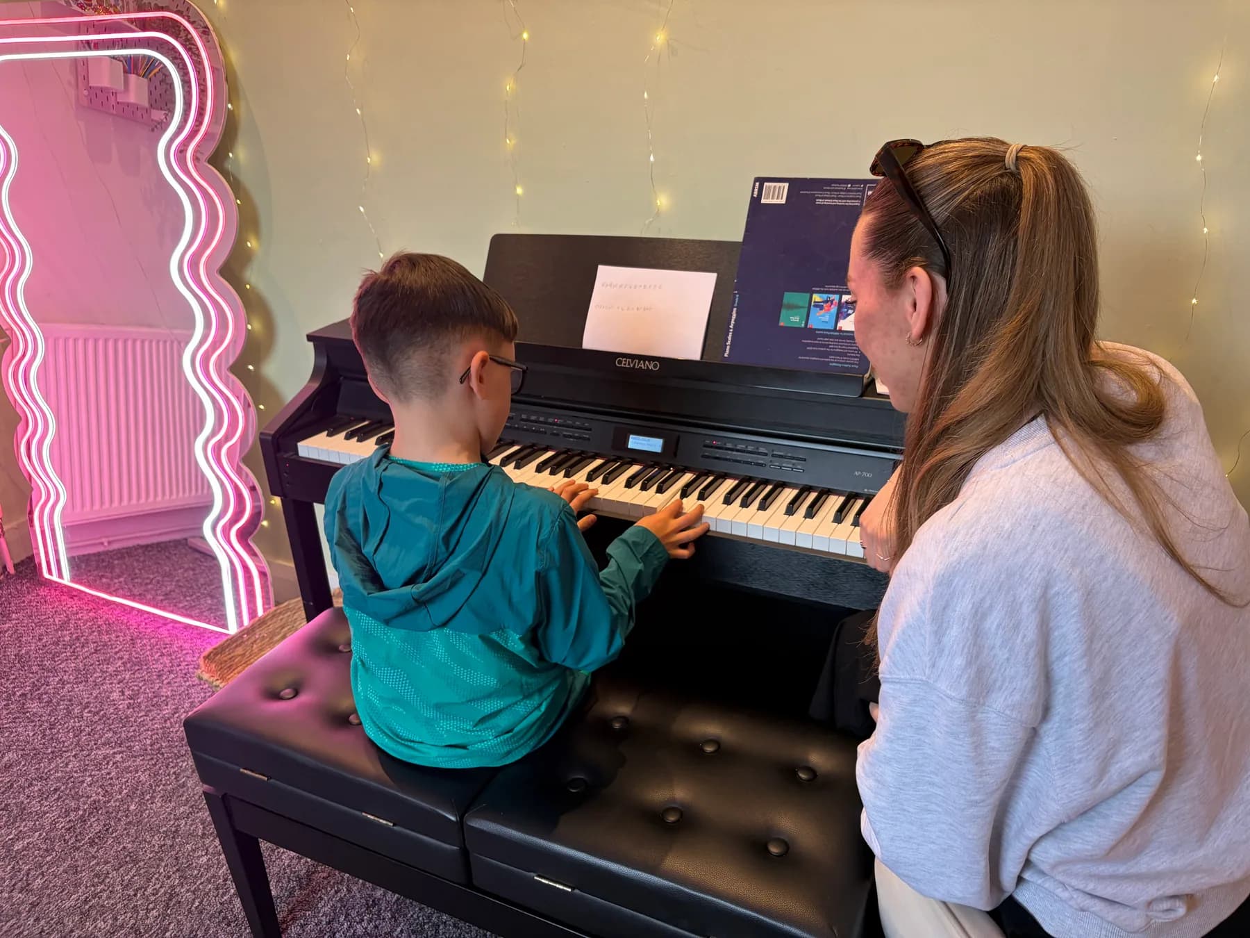A piano teacher supporting a young student